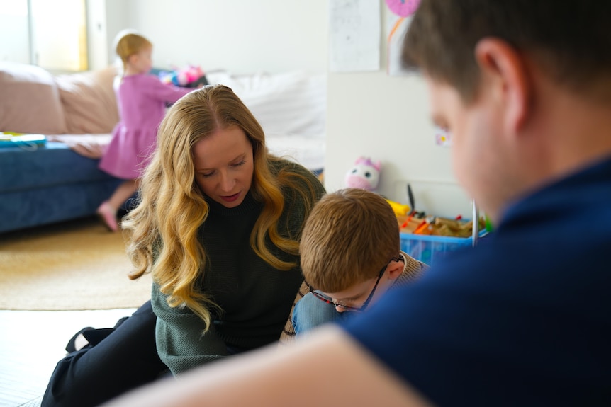 Christine and Warren kneel on the floor, playing with their son Patrick.