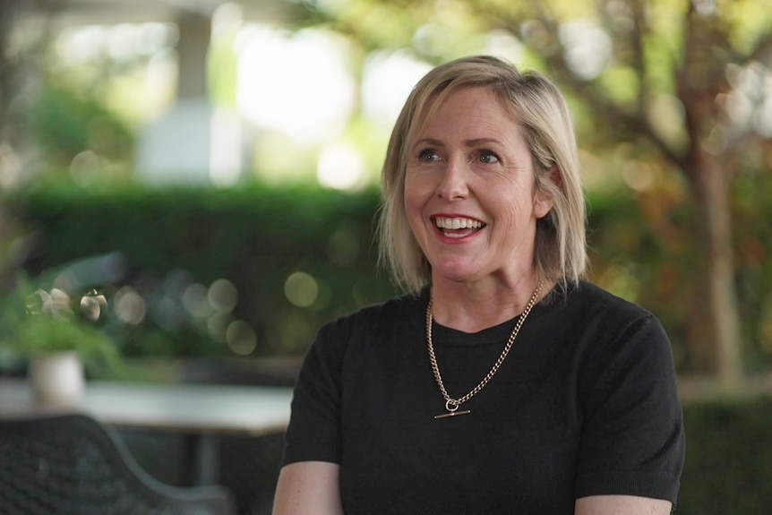 A blonde woman smiles at the camera